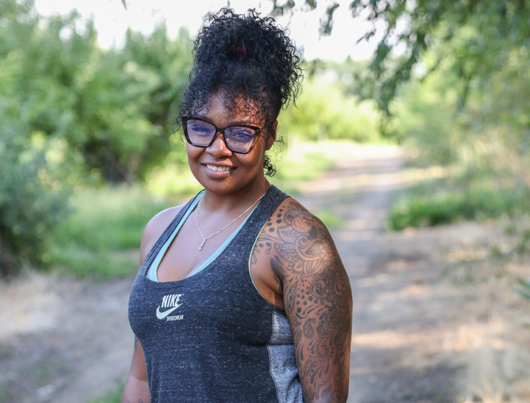 Dionna standing on a gravel rural road smiling in a black dress