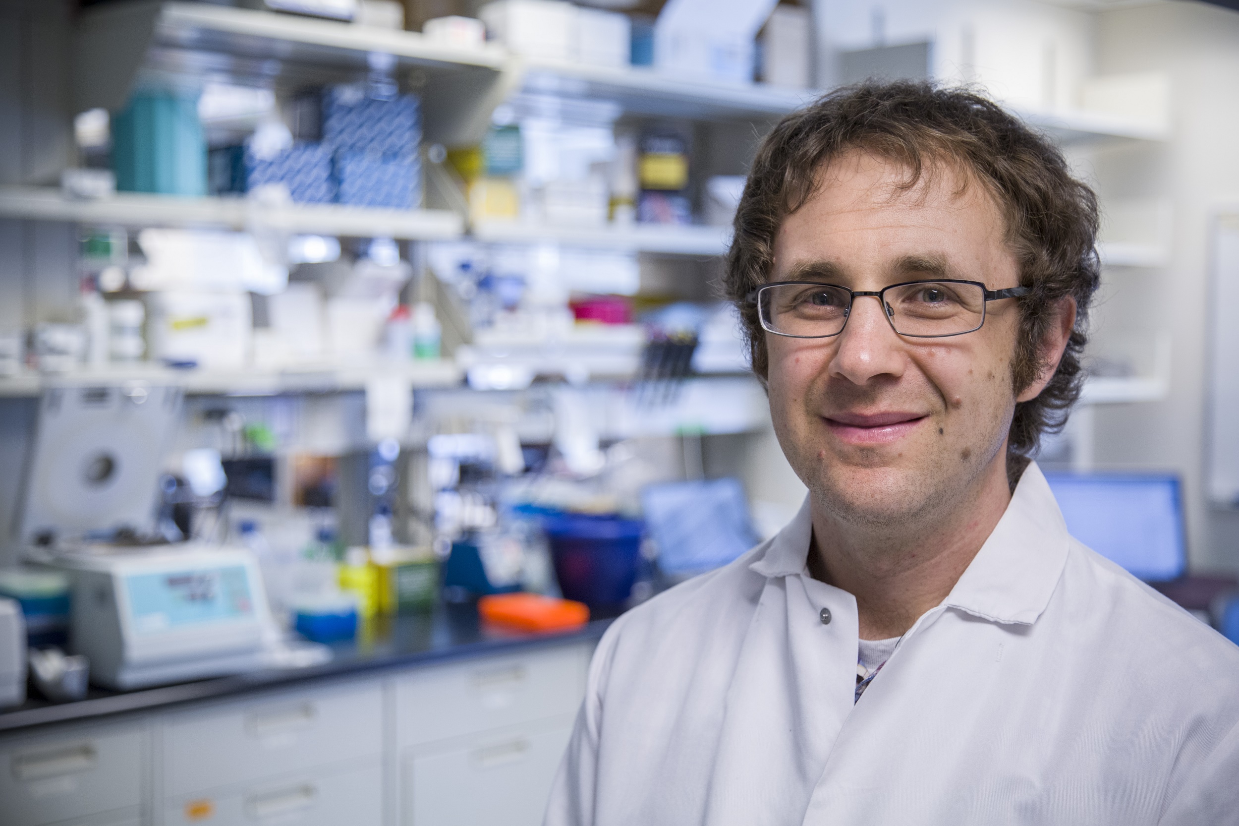 Dr. Jesse Bloom wearing a lab coat in a medical lab