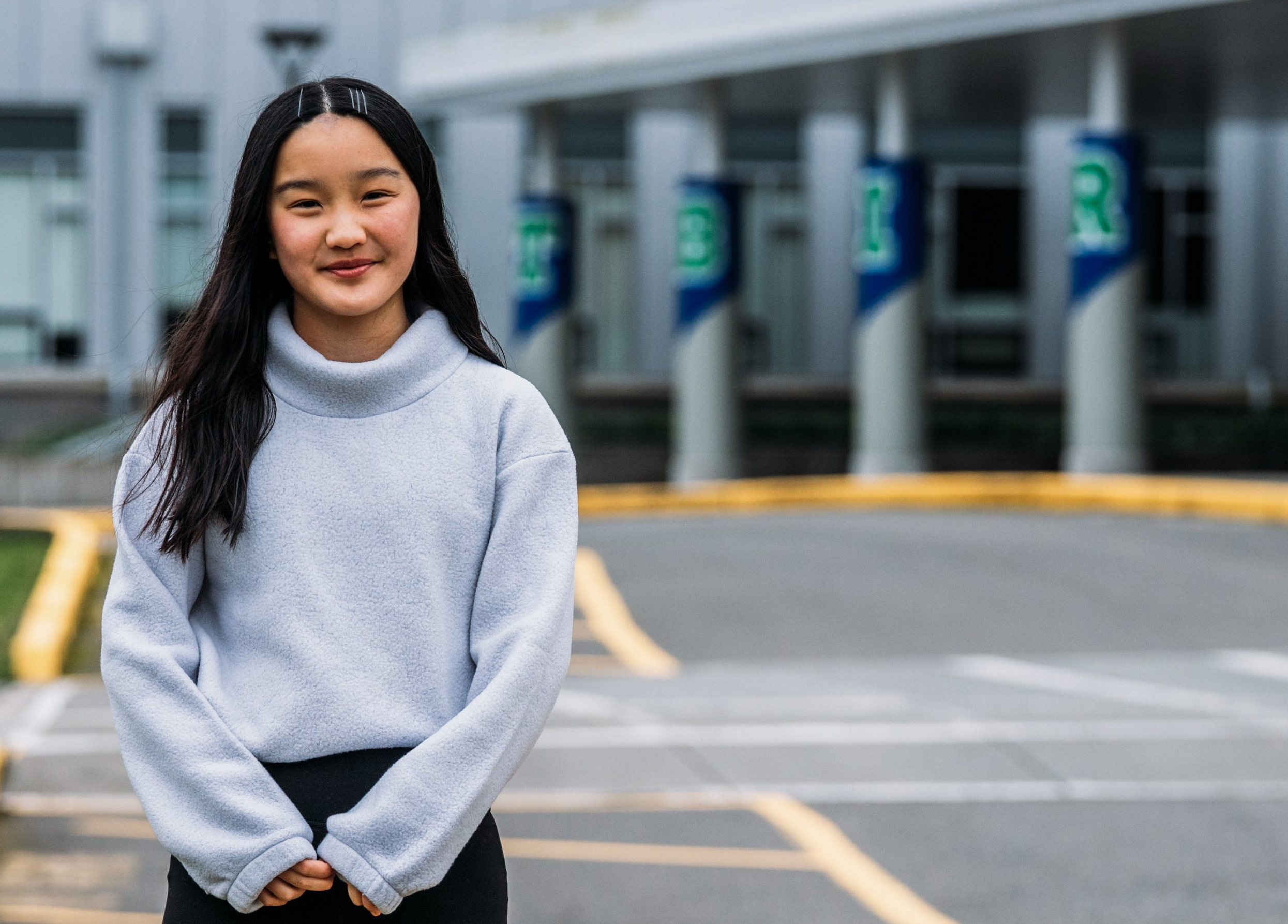 Yubi dressed in grey and black standing in a parking lot