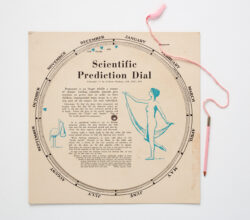 Image of a 1930's era mensuration prediction dial made of paper with a pencil attached with pink thread.