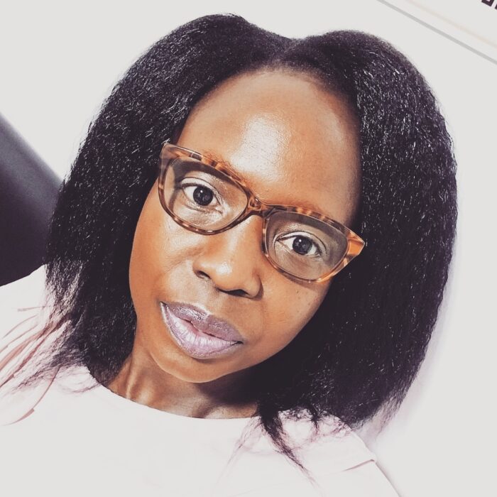 Roseline wearing glasses and a white shirt looking at the camera with a white background.