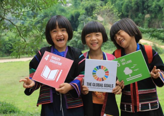 Young Asian school girls smiling and UN Global Goals signs.