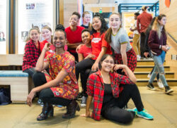 A group of teen dance performers smiling after a performance at the Discovery Center