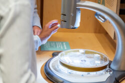 A visitor's hand reaches for a microscope in the Discovery Center.