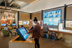 A visitor interacts with a screen in the Take Action gallery of the Discovery Center while others in the background enjoy the space.