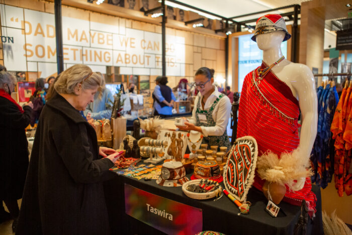 A visitor stops at Taswira's vendor table to purchase a gift from the vendor at the annual Giving Marketplace.