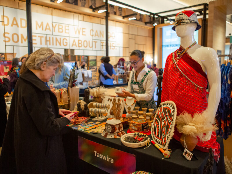 A visitor stops at Taswira's vendor table to purchase a gift from the vendor at the annual Giving Marketplace.