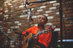 Musician Naomi Wachira singing and playing guitar.