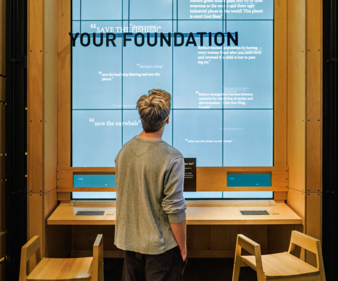 visitor in front of the "Your Foundation" display screen
