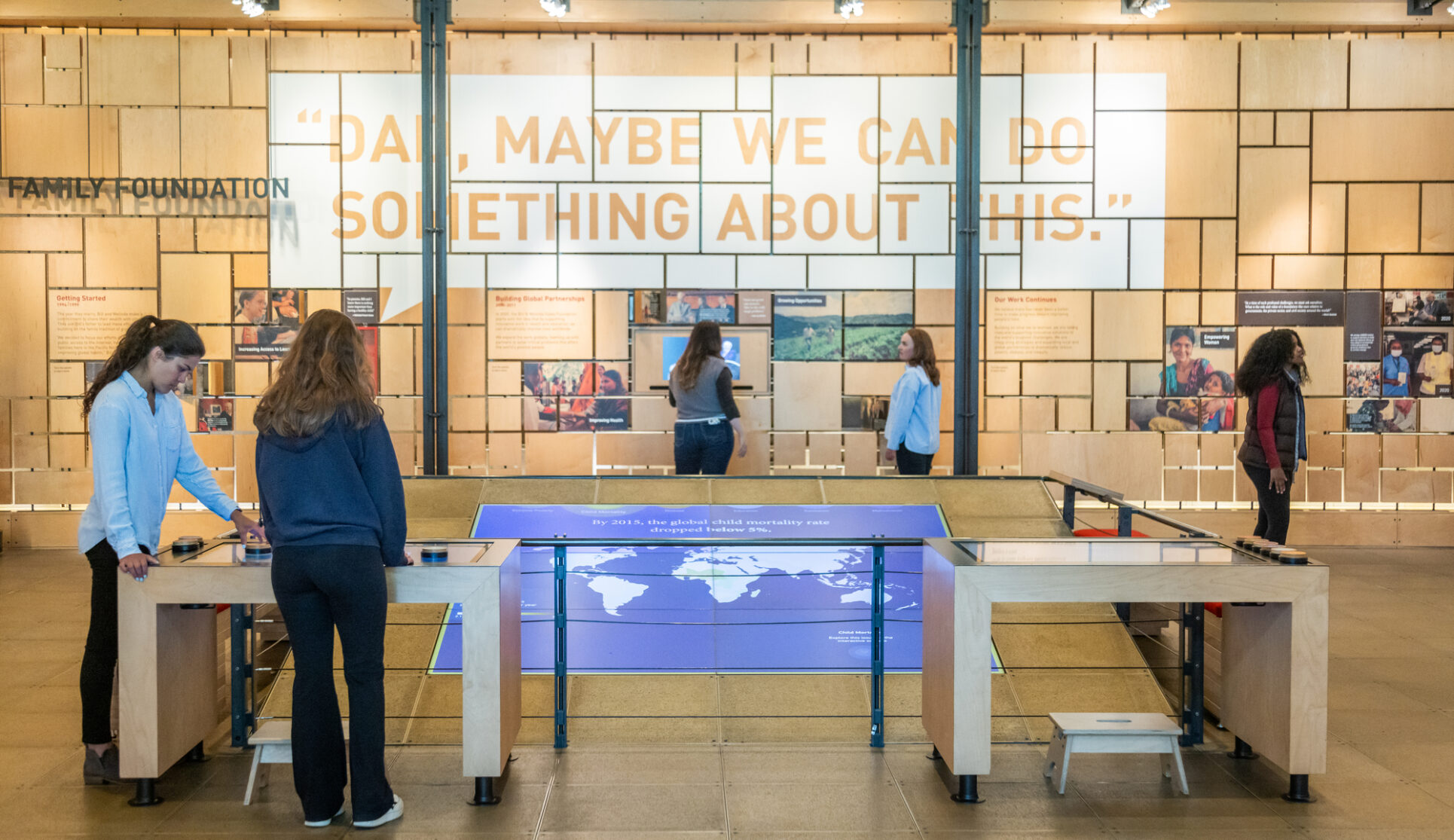 A gallery shot of the "Our Work" gallery featuring visitors looking at exhibits on display in the Discovery Center.