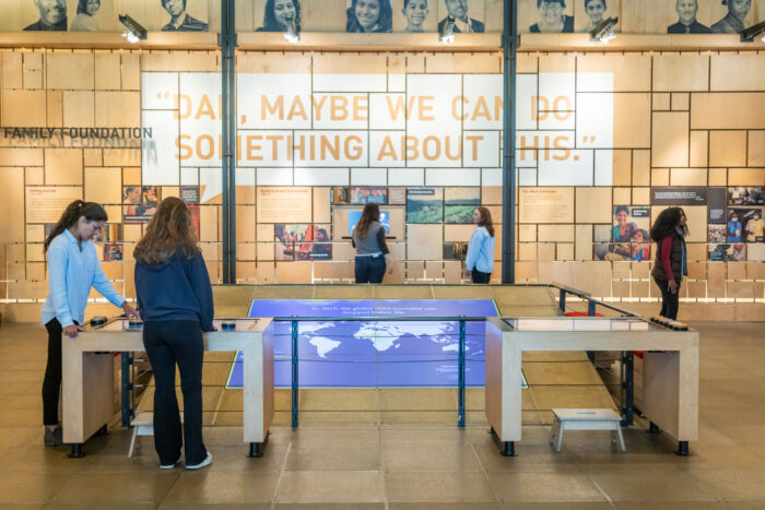 A gallery shot of the "Our Work" gallery featuring visitors looking at exhibits on display in the Discovery Center.