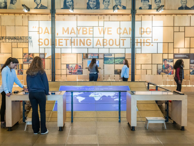 A gallery shot of the "Our Work" gallery featuring visitors looking at exhibits on display in the Discovery Center.