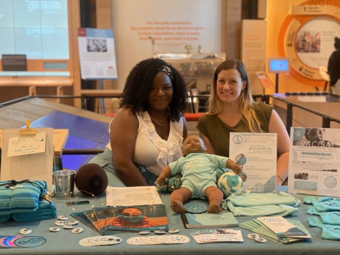 Two women from our partner organization Nurturely smiling for the camera while meeting visitors in the Discovery Center.