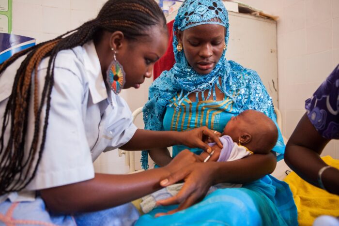 An infant receives a vaccine in Senegal while being held by its mother.