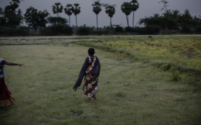 Women walks in a field with her back to the camera. 