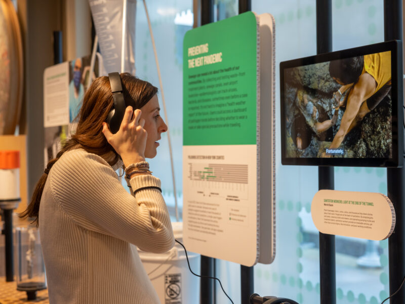 Woman wears headphones to listen to a video installed in the "A Better Way to Go" exhibition.