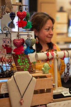 Visitor visits vendor's table and shops holiday gifts that give back during the annual Giving Marketplace