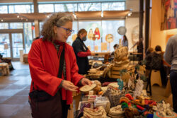 Visitor visits vendor's table and shops holiday gifts that give back during the annual Giving Marketplace