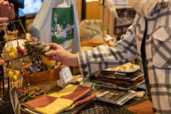 Visitor visits vendor's table and shops holiday gifts that give back during the annual Giving Marketplace