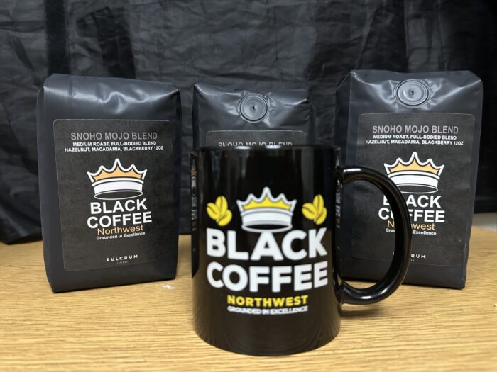 Three coffee bags with a "Black Coffee Northwest" black mug in front.