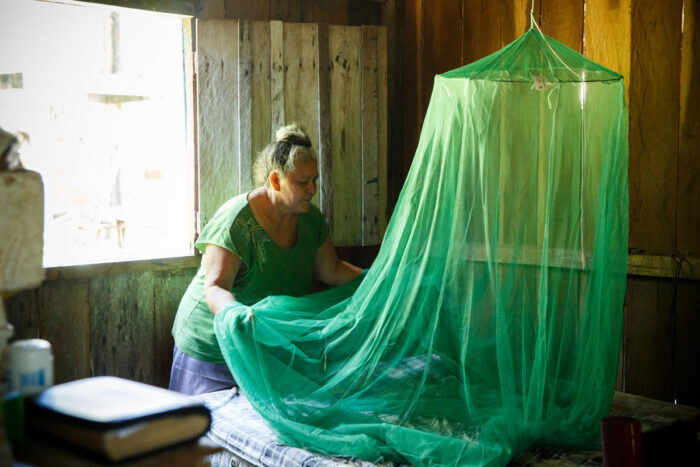 Women installs a mosquito net around her bed