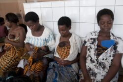 Mothers sit together on a bench in the Kangaroo Mother Care unit of a hospital.
