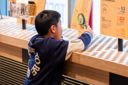 Young boy uses a magnifying glass to examine a label at the Discovery Center