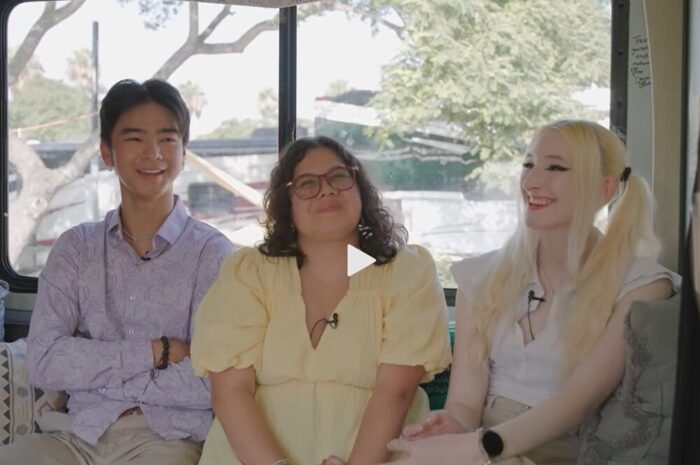 Three young adults sitting on a couch smiling and laughing together