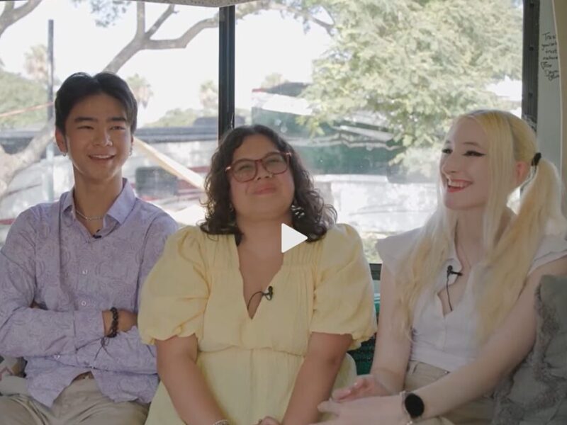 Three young adults sitting on a couch smiling and laughing together